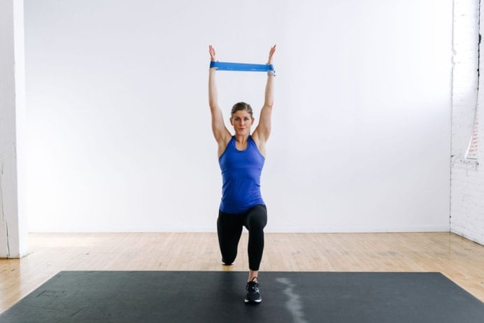 woman performing a lunge and overhead press with a resistance band