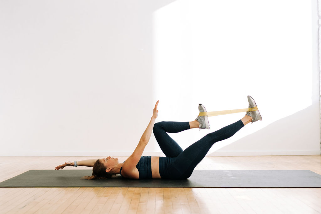 woman performing a dead bug exercise with resistance band in a resistance band ab workout