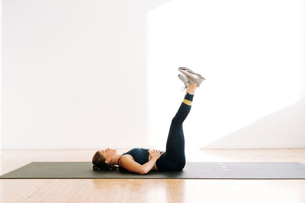 woman performing leg lowers with a mini band in a resistance band ab workout