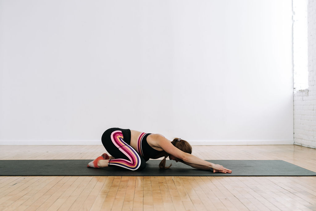 woman holding child's pose as part of the best upper body stretches