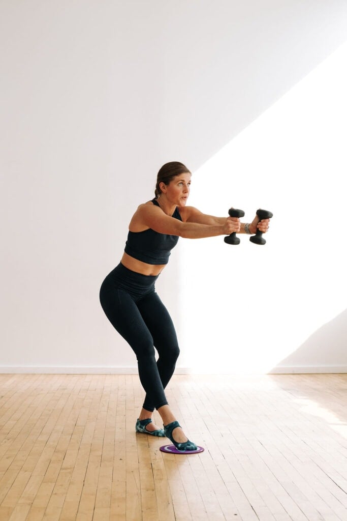 woman performing a dumbbell press and leg press with a glider in a slider workout