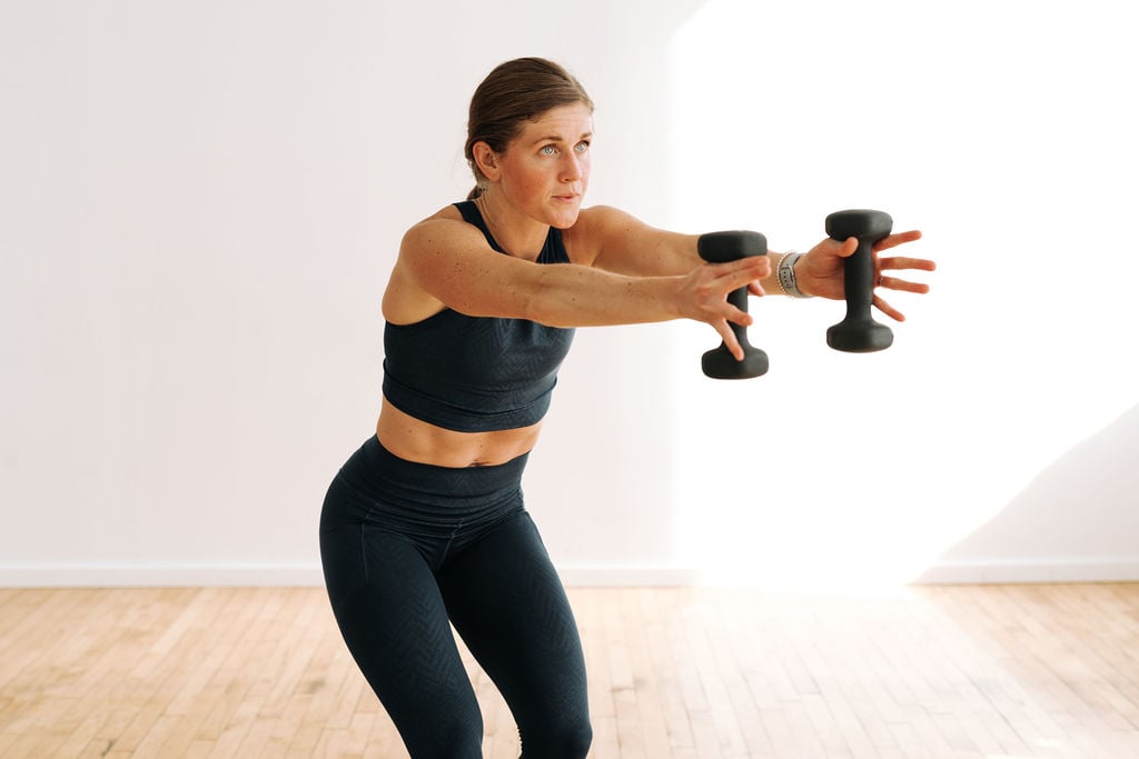 woman performing a dumbbell press out in a barre workout