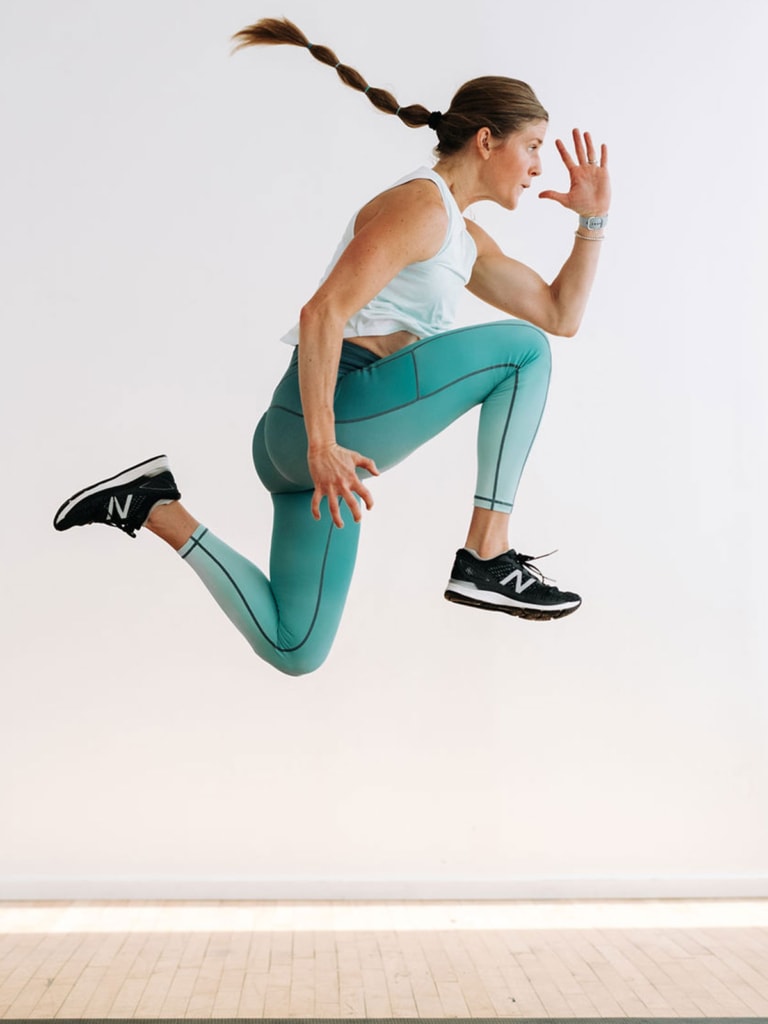 woman performing a split jump in air as part of an explosive workout