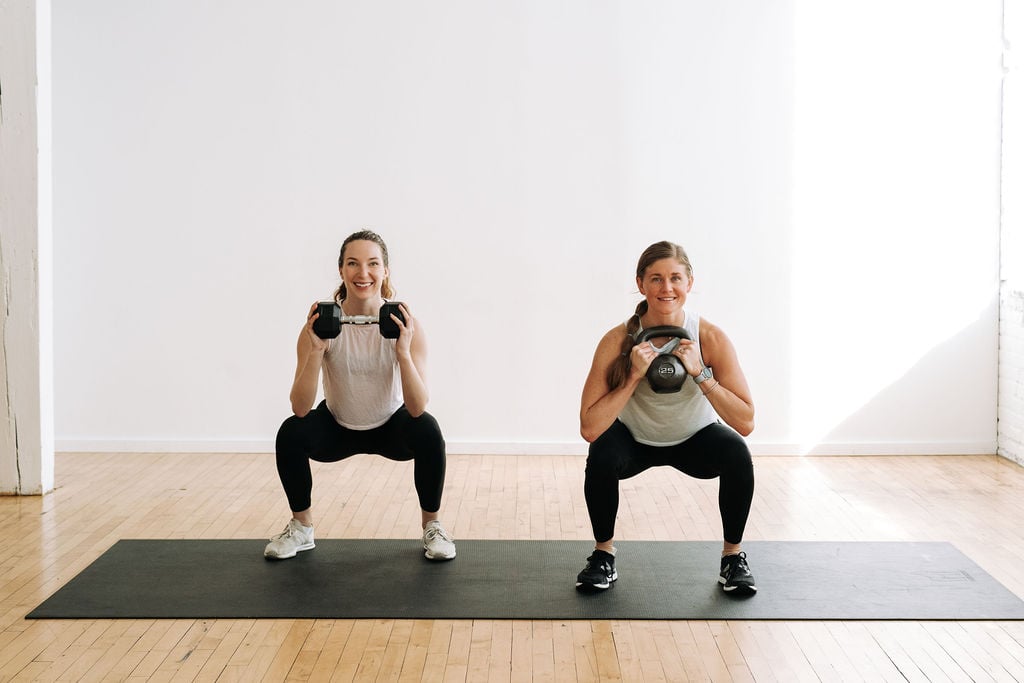 two women performing a kettlebell goblet squat hold in a full body kettlebell cardio workout
