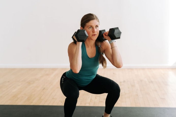 women performing a front squat with dumbbells