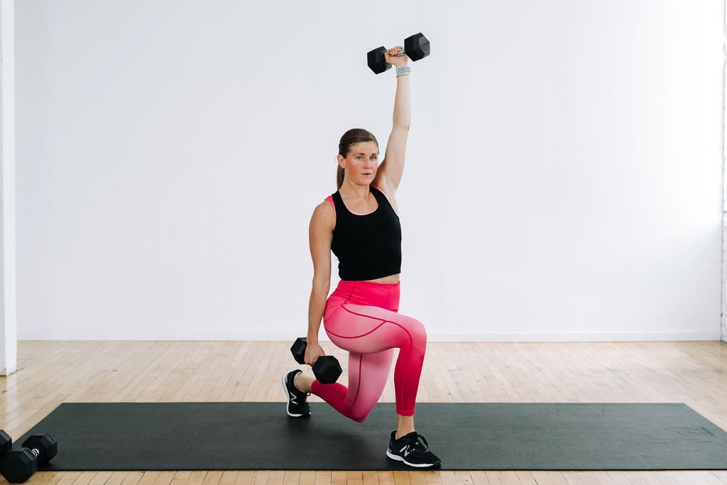 women performing a lunge with one dumbbell overhead during a full body dumbbell workout