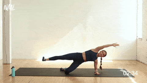 woman performing a modified side plank and toe touch in an ab workout for beginners