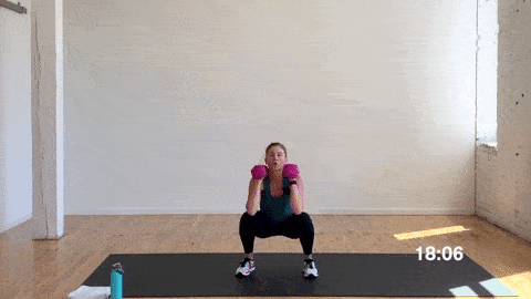 woman performing a dumbbell squat in a superset workout