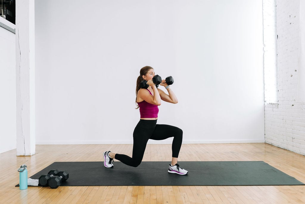 woman performing a reverse lunge with dumbbells front racked in a Legs and Chest Workout