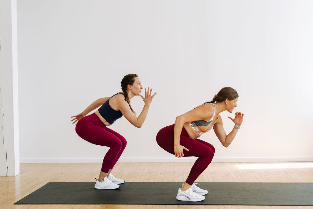 Two women performing a loaded squat in a bodyweight workout for women. Best bodyweight workout for women in a Tabata format.