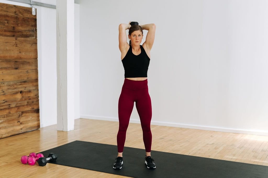 woman performing an overhead tricep extension in a bicep and tricep workout