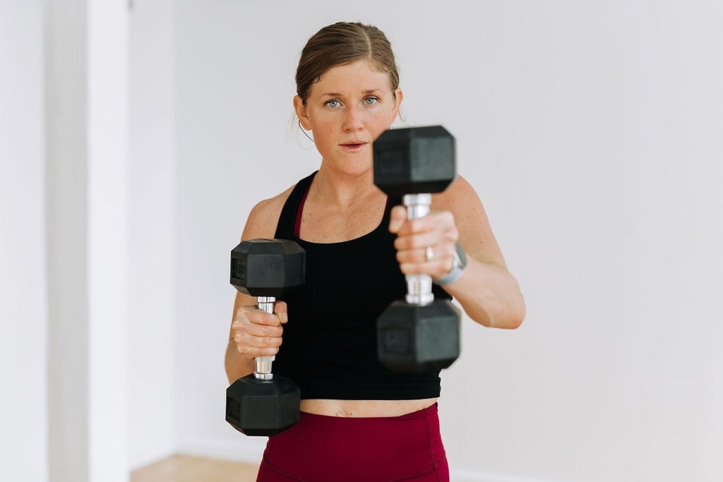 woman performing an alternating dumbbell press out in an upper body workout for women