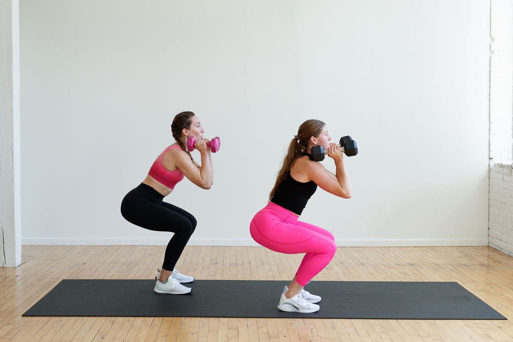 two women performing a front rack dumbbell squat in a HIIT strength and conditioning workout