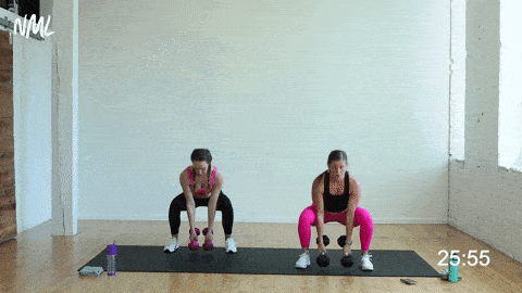 two women performing a dumbbell squat curl and press in a strength and conditioning workout