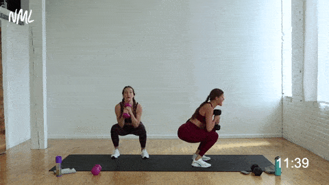 two women performing a goblet squat and 45 degree press out in a full body workout