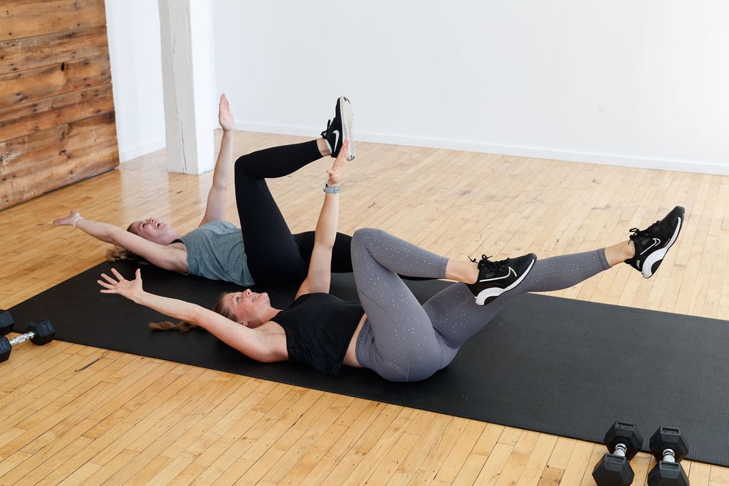 two women performing dead bug exercise during full body postpartum workout