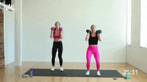 two women performing a dumbbell push press in a strength and conditioning workout