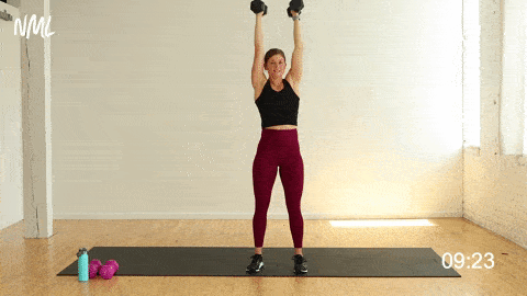 woman performing a single arm curl and overhead press in a shoulder, bicep and tricep workout