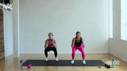 two women performing weighted squat quick split taps in a strength and conditioning workout