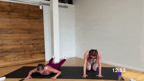 one woman performing superman rear flys and one woman performing bird dog as a modification in a bodyweight workout at home