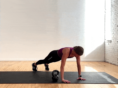 woman performing a push up and kettlebell pass in a total body workout