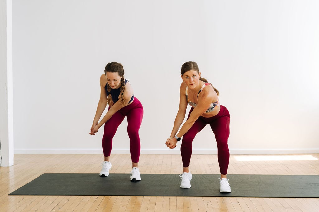 two women performing a bodyweight wood chop cardio exercise in a cardio workout at home