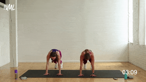 two women performing a step in burpee and 2 front lunges in a cardio workout