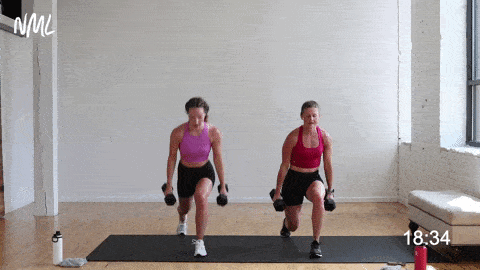 two women performing a lunge jump curl and press in a high intensity workout at home
