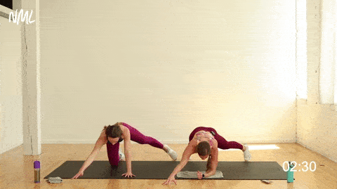 two women performing a forearm plank and alternating star taps in a cardio workout
