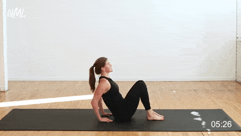 woman performing v-sit alternating leg extensions in a lower ab workout at home