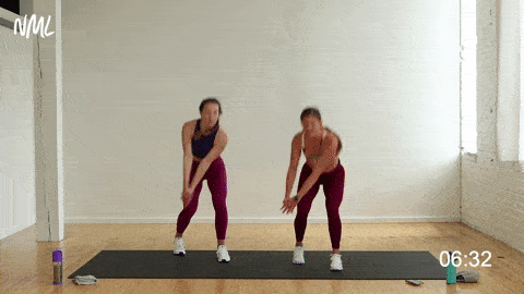 two women performing a staggered squat and wood chop in a cardio workout