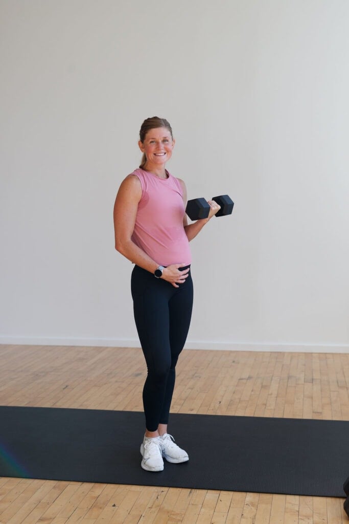 pregnant woman holding a dumbbell in a bicep curl as part of the 8 Best First Trimester Exercises