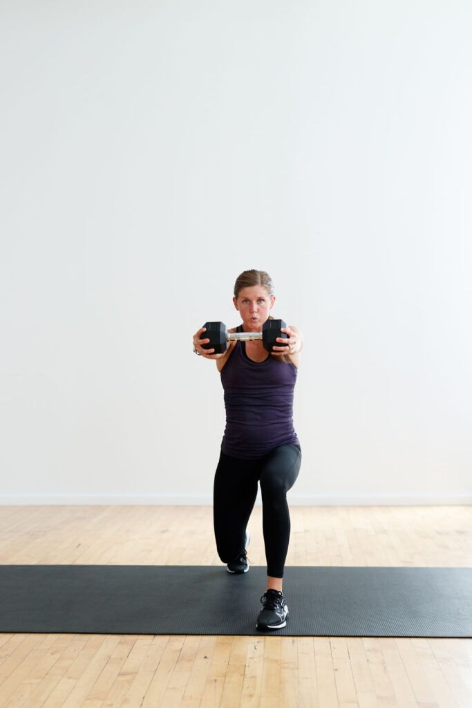 woman performing a lunge and dumbbell press out in a strength and kickboxing workout