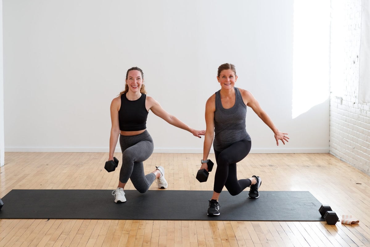 two women performing a crusty lunge with dumbbells and resistance bands during a 10 minute leg workout. 