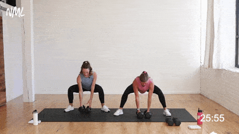 two women, one pregnant, performing a wide squat and back row as a first trimester exercise