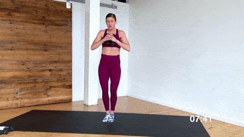 woman performing plie toe stand jumps with light weights in a barre workout