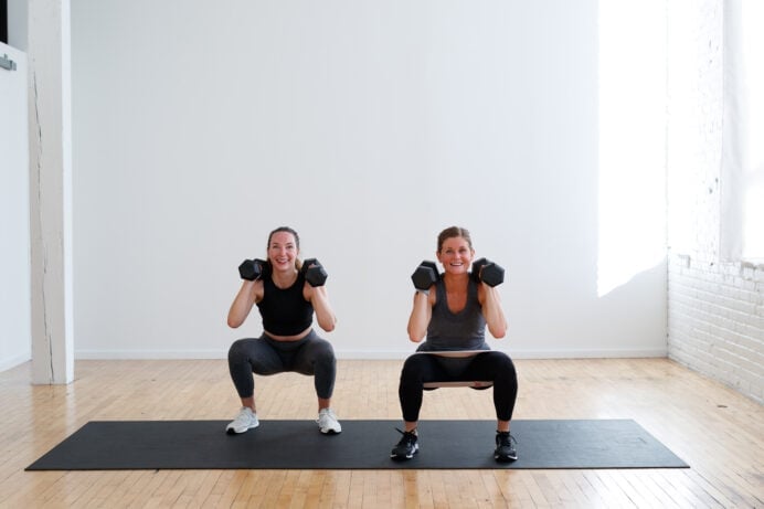power legs | two women at the bottom of a standard squat with dumbbells front racked during a 10-minute leg workout