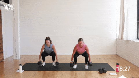 two women, one pregnant, performing a squat, curl and press in a first trimester strength workout