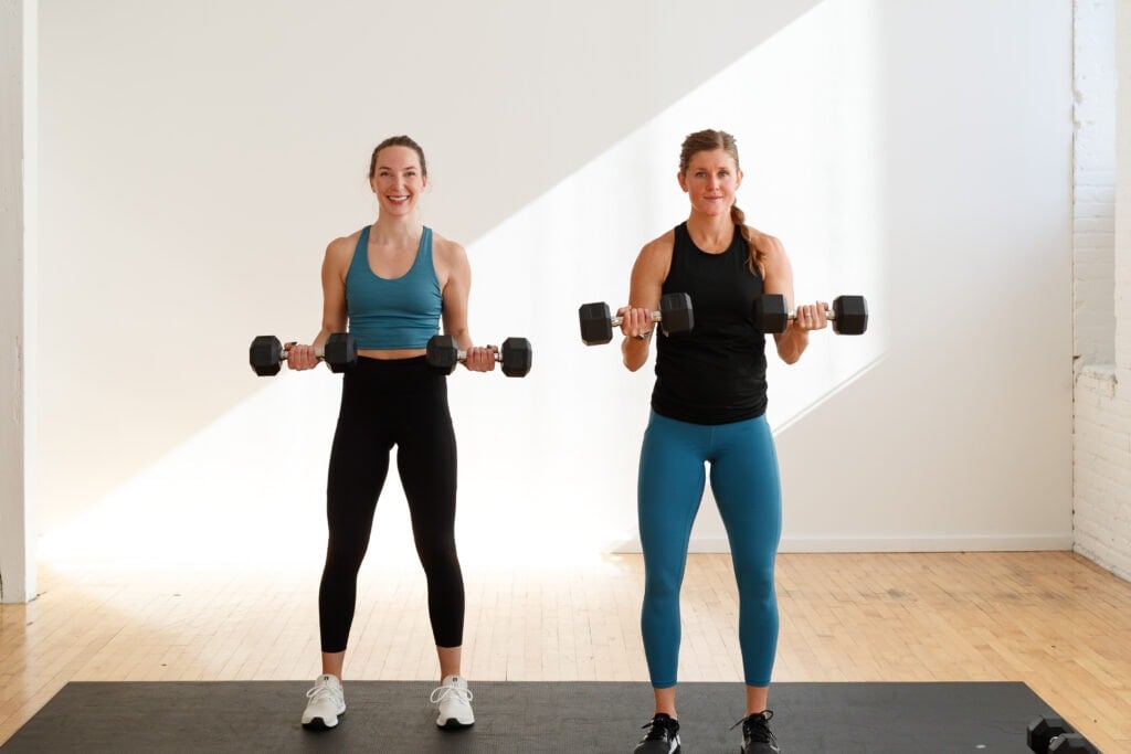 two women performing a dumbbell bicep curl hold in an arms and abs workout for women