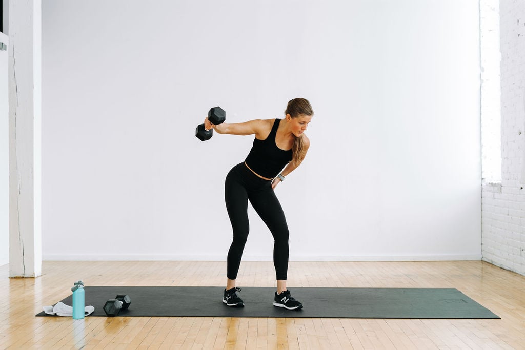 woman performing a single arm dumbbell fly in a back workout