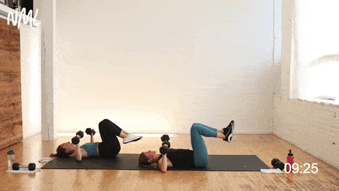 two women performing a chest press and leg extensions working the arms and abs at the same time