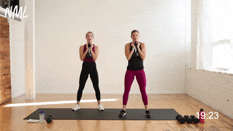 two women performing a dumbbell goblet squat in a leg superset workout
