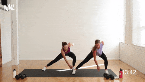 two women performing a lateral lunge two high knees in a first trimester workout