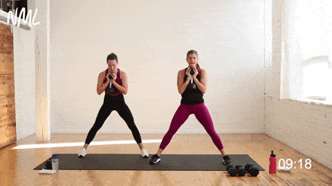 two women performing a lateral squat in a leg superset workout
