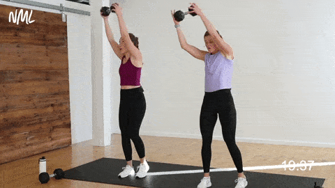 two women performing a lunge and cross body chop in a pregnancy workout