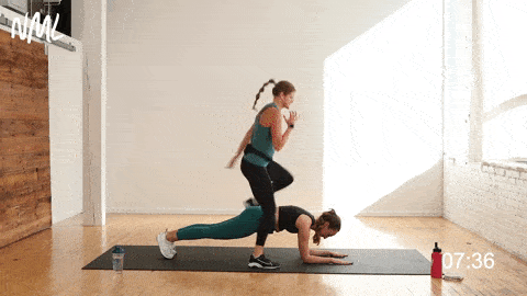 one woman holding a plank and one woman performing plank hop overs in a partner workout