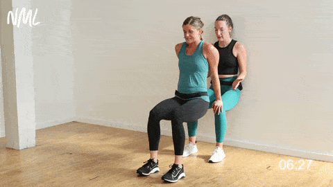 one woman performing a wall sit and one woman performing tricep dips as part of the best partner exercises no equipment