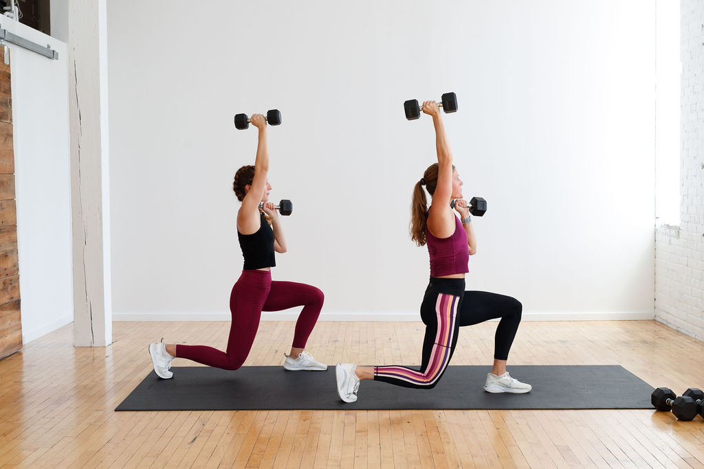 two women performing a lunge and overhead press as part of a HIIT leg day workout
