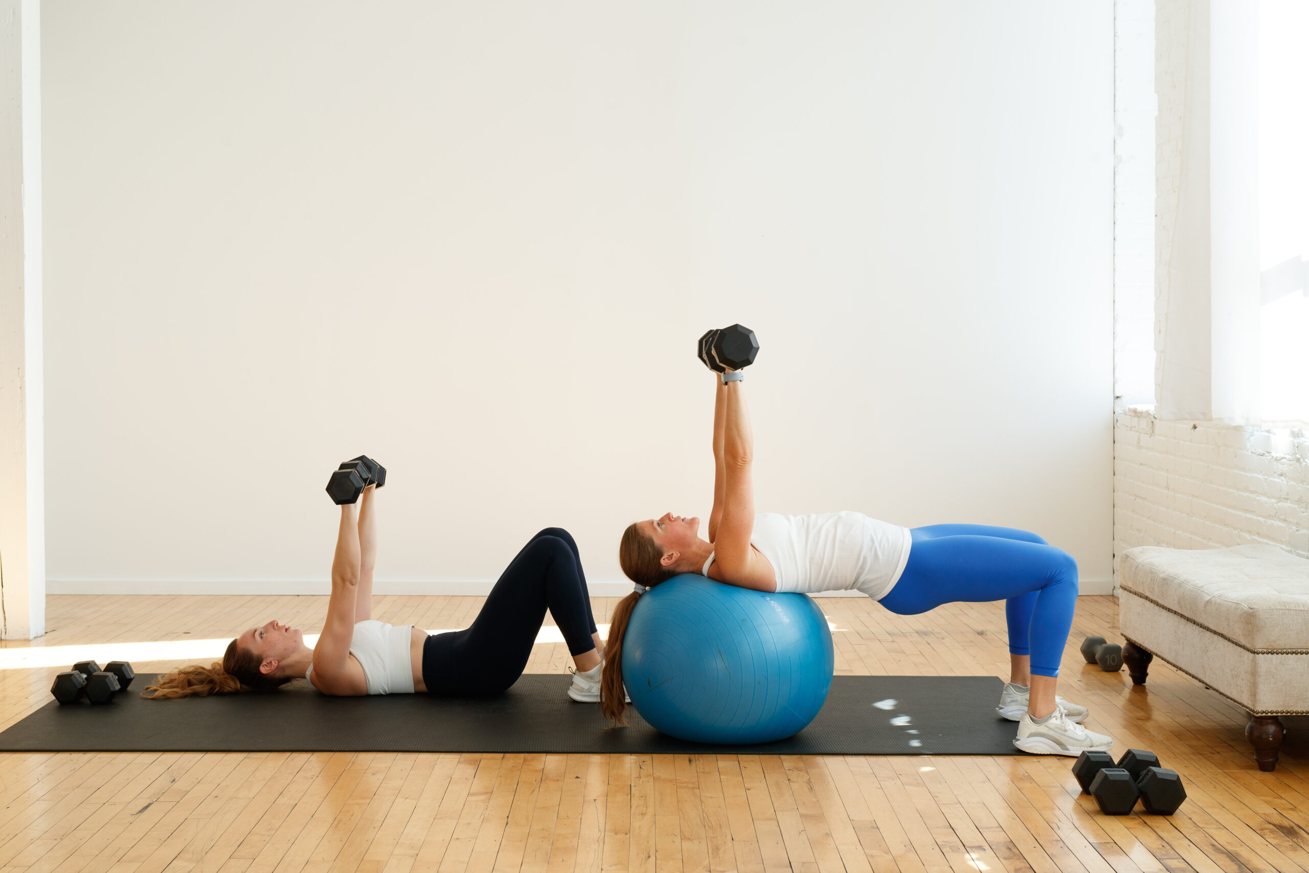 25-Minute Chest and Arm Workout. Dumbbell Chest Press Exercise. Two women holding dumbbells performing a dumbbell chest press. 