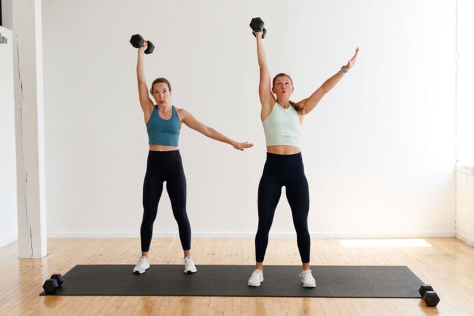 two women performing a single arm push press exercise hiit arms hiitstrong day 7